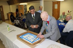 Paul Napper cuts his cake, while Pastor Flores looks on, that was at the luncheon given in his honor after being conferred the title of Deacon Emeritus on June 12, 2016. 