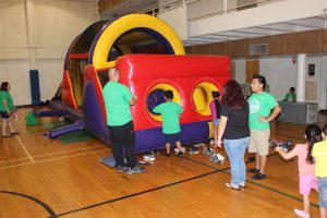 Parents help children climb inside an inflatable obstacle challenge course in the gym at Vacation Bible School on July 30, 2015. 